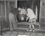 Two students move old chemistry equipment, 1947