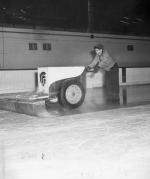 A man floods the hockey arena ice, date unknown