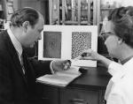 Barnett Rosenberg and Loretta Van Camp with photographs of normal bacteria and bacteria that have been treated with platinum.