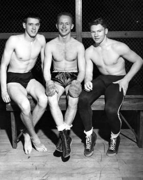 Boxer Chuck Davey sits with two other athletes, 1940 ca. title=Boxer Chuck Davey sits with two other athletes, 1940 ca.